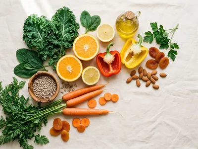 Farbenfrohe Auswahl vitaminreicher pflanzlicher Lebensmittel — Paprika, Karotten, Blattgemüse, Nüsse, Zitrusfrüchte und Beeren